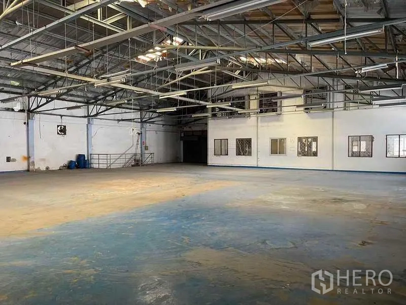 Factory for rent in Phra Samut Chedi, Samut Prakan - Spacious warehouse floor with exposed steel trusses and side windows.