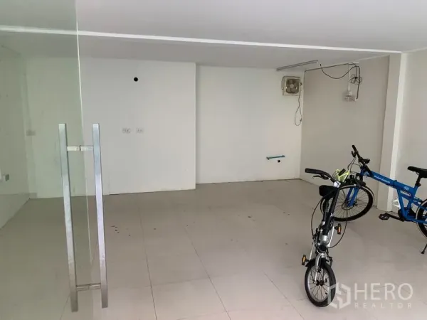 Retail Space for rent in Watthana, Bangkok - Open interior with white tiled floor, glass door handle, plain walls and basic wiring.