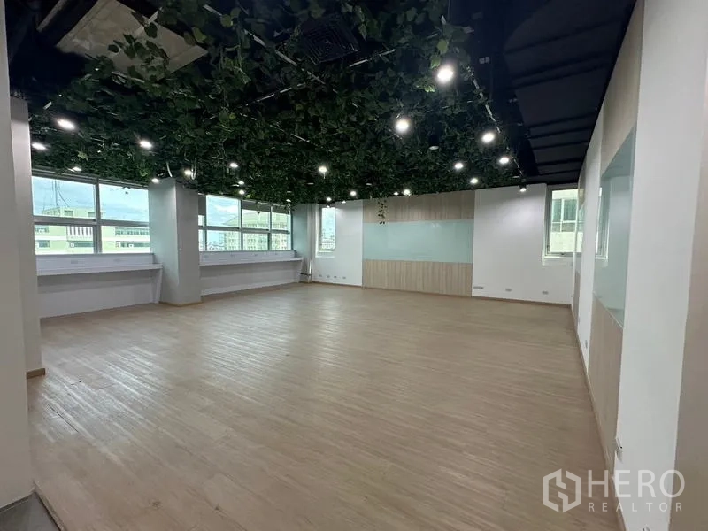 Office Space for rent in Ratchathewi, Bangkok - Corner open space with wide windows, green ceiling decor and laminated floors.