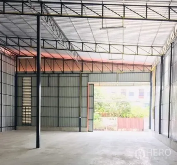 Warehouse for rent in Khan Na Yao, Bangkok - Spacious warehouse interior with high steel truss roof, concrete floor, and wide loading door.