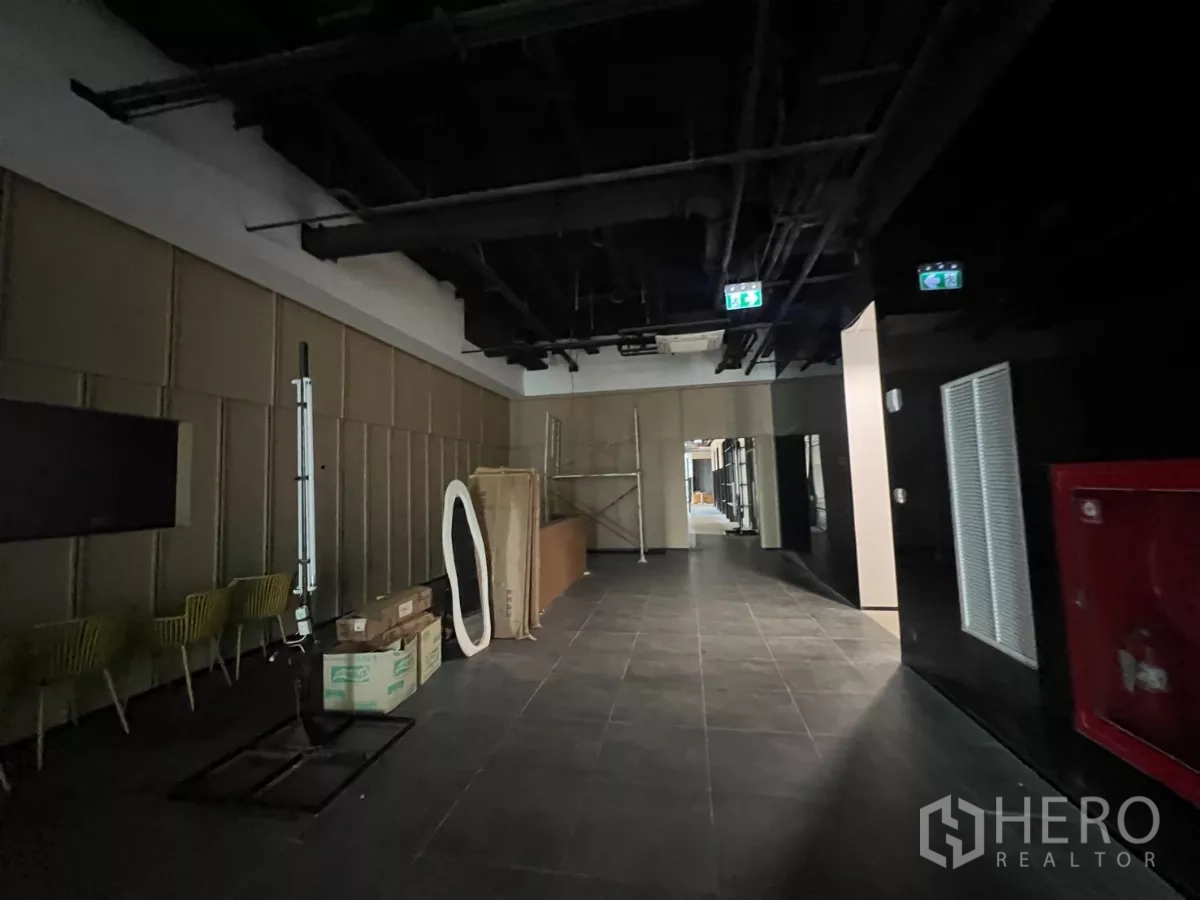Retail Space for rent - Common area lobby with dark tiled flooring, exposed ceiling services and emergency exit signs.