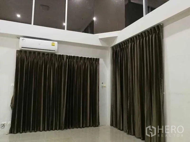 Home Office for rent in Khlong Toei, Bangkok - Corner of living area with split-type air conditioner and tall dark drapes.