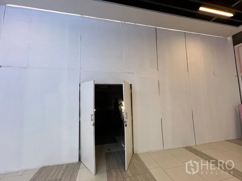 Retail Space for rent - White storefront facade with double swing doors opening to a retail unit in a mall corridor.
