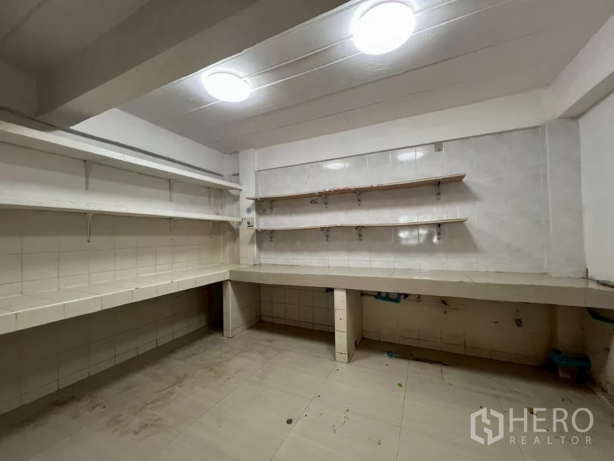 Shophouse for rent in Watthana, Bangkok - Back-of-house kitchen with tiled counters, shelving, and easy-clean surfaces.