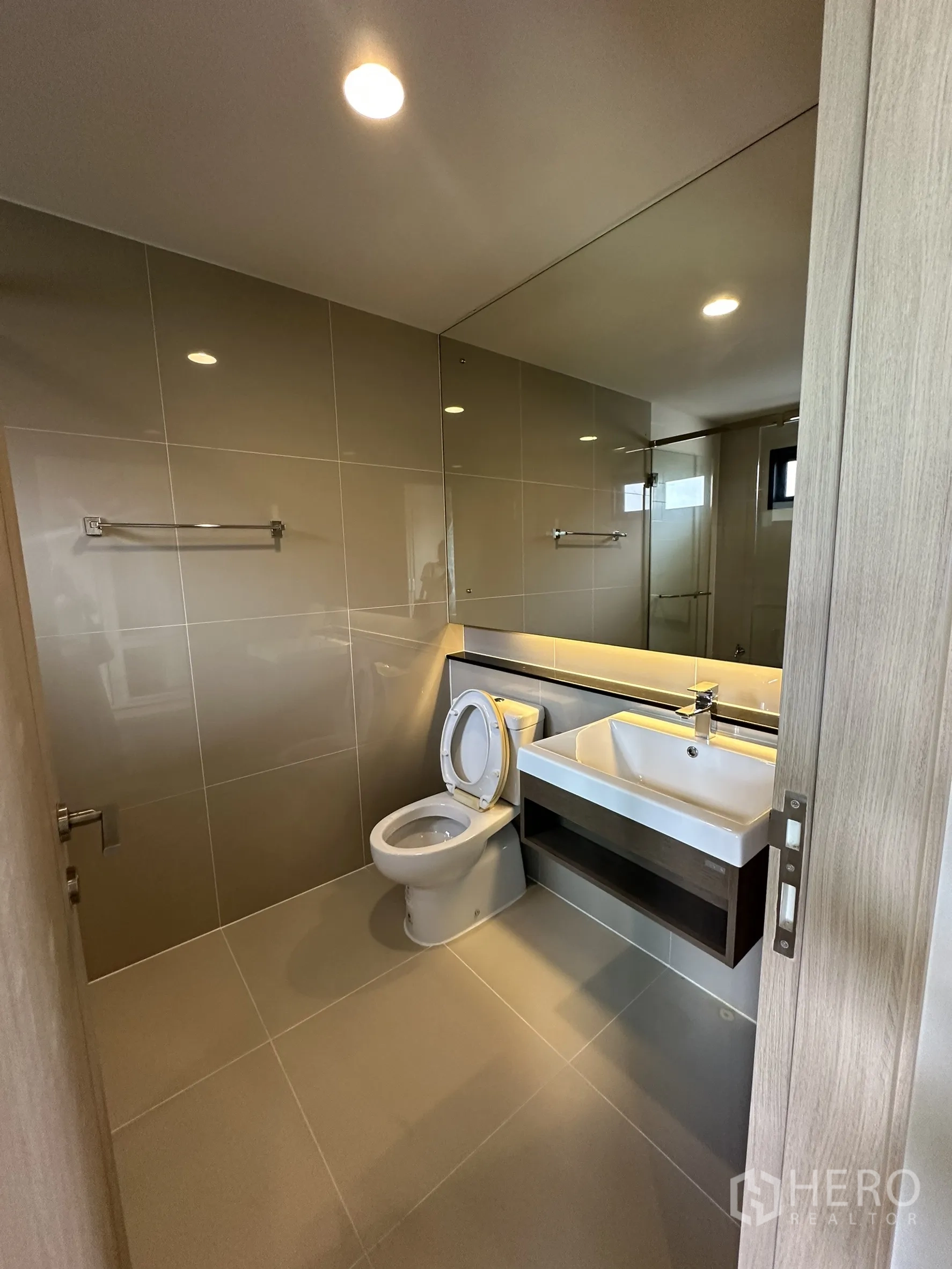 Detached House for sale in Lam Luk Ka, Pathum Thani - Guest bathroom with large mirror, modern vanity and tiled walls.