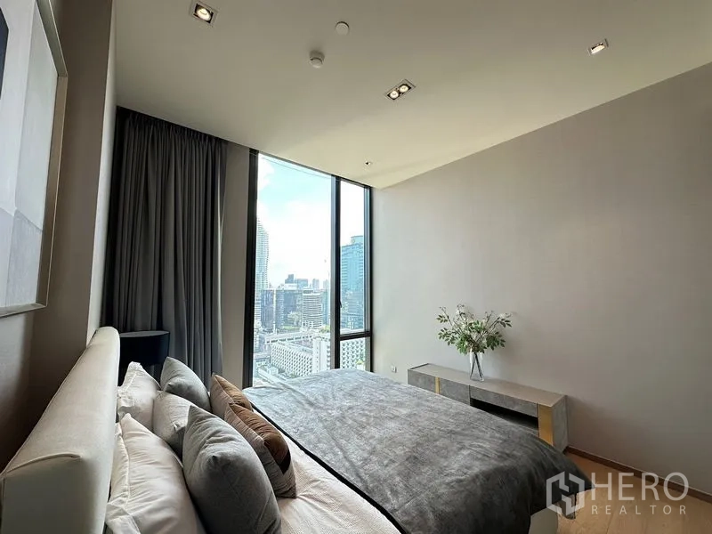 Condominium for rent in Pathum Wan, Bangkok - Bedroom angle showing tall windows framing the downtown skyline.
