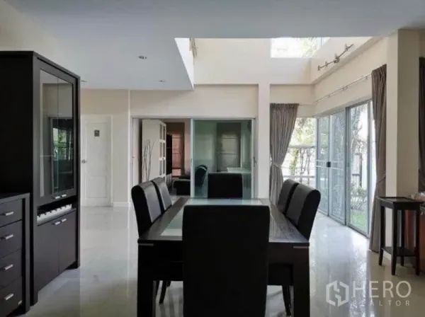 Detached House for rent in Bang Kapi, Bangkok - Dining area with high ceiling and skylight, six‑seat table and wide glass doors opening to the garden.