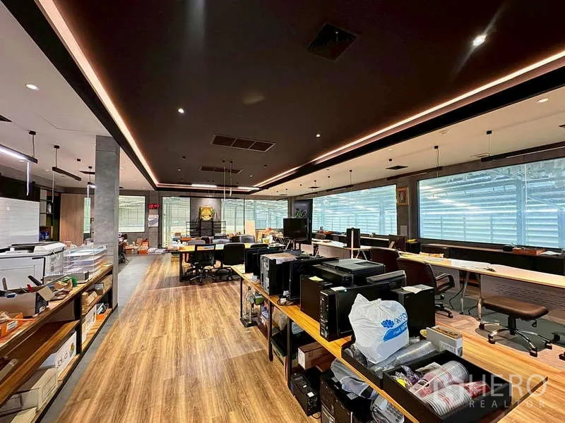 Warehouse for rent in Prawet, Bangkok - Open-plan office area with desks, wood floors, and LED strip lighting.