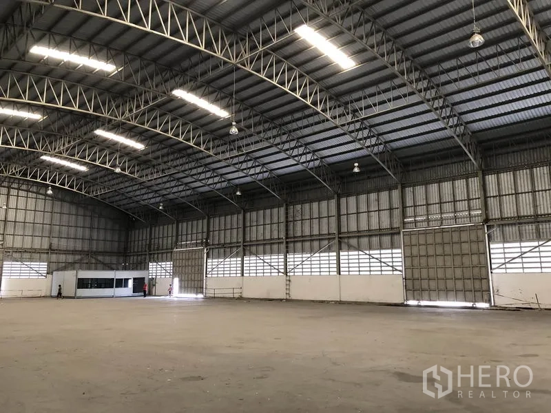 Warehouse for rent in Pathum Thani - Side view of the interior with rows of roller doors, high-bay lights and ventilated panels.