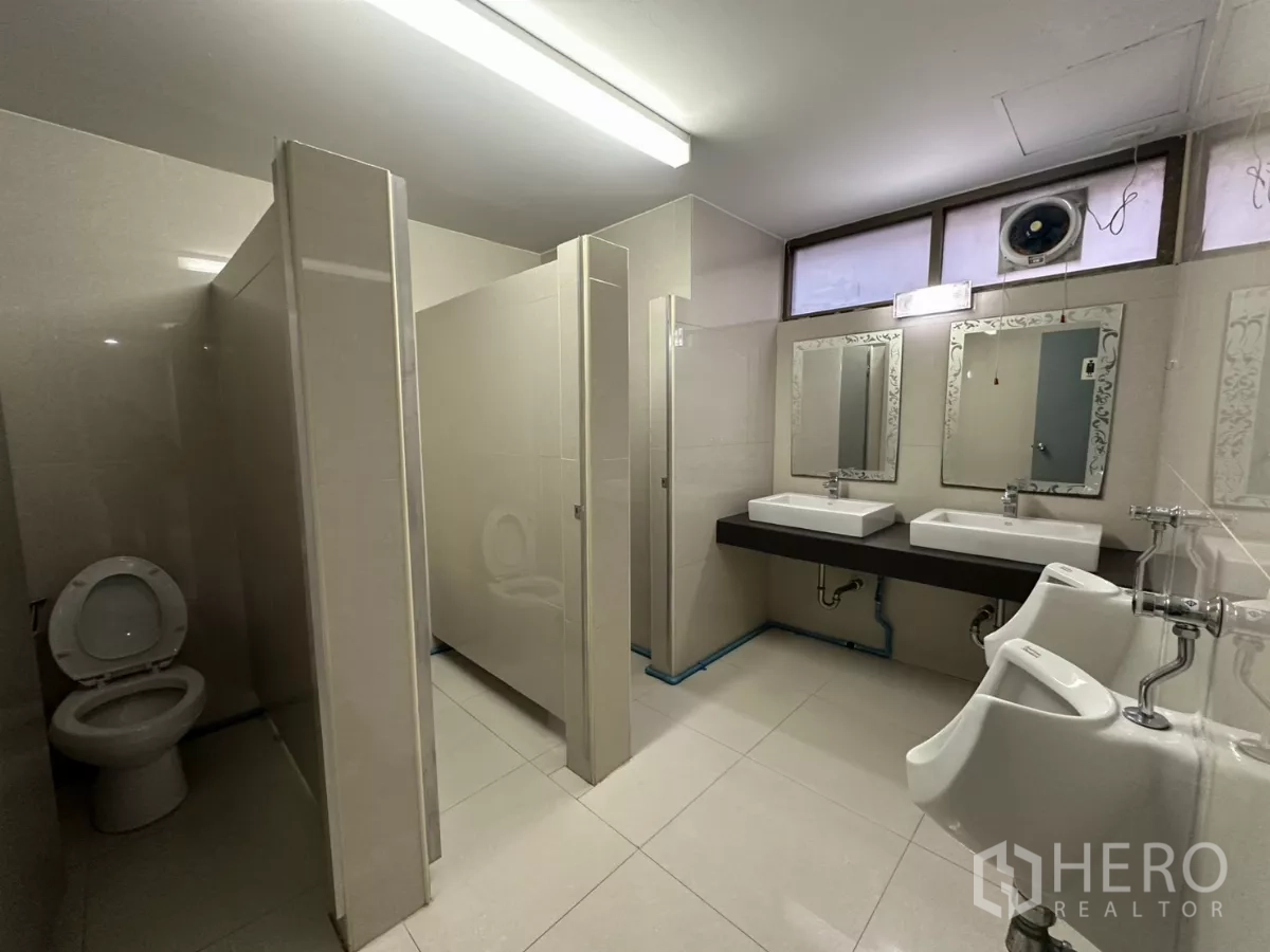 Office Space for rent - Shared restroom with stalls, urinals, double sinks and mirrors.