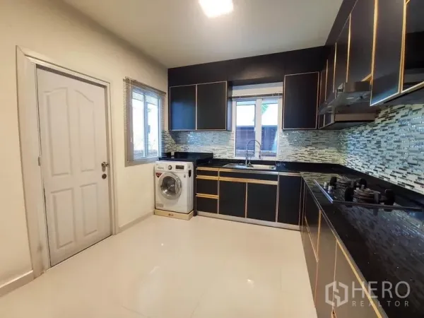 Detached House for rent - U-shaped modern kitchen with black cabinets, mosaic backsplash and a washing machine
