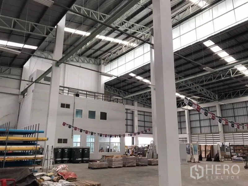 Warehouse for rent in Sai Noi, Nonthaburi - Spacious warehouse interior with steel truss roof, skylight panels and mezzanine office block.