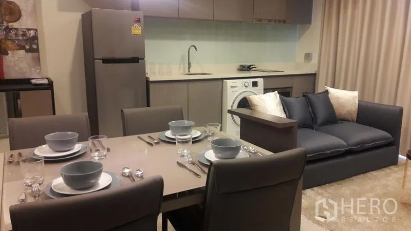 Condominium for rent in Khlong Toei, Bangkok - Open-plan kitchen with fridge, washer, and four-seat dining next to sofa