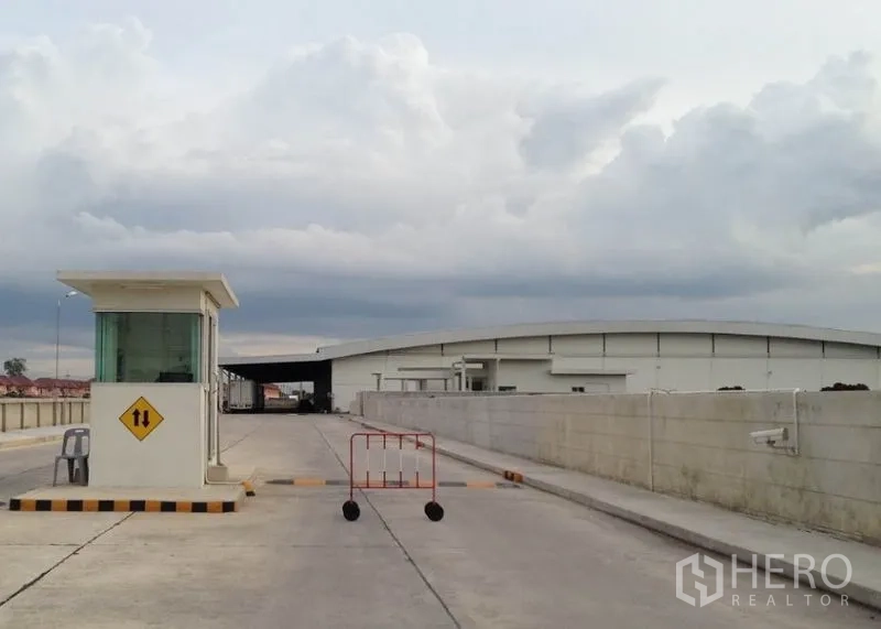 Warehouse for rent in Phra Nakhon Si Ayutthaya - Gated industrial entrance with guard booth and wide truck-friendly concrete road.
