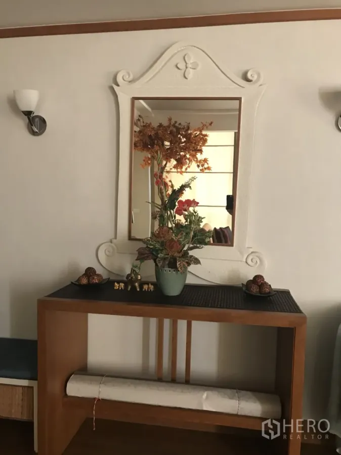 Condominium for rent in Pathum Wan, Bangkok - Entry console with wooden table, ornate framed mirror, and vase of dried flowers in a Bangkok condo.