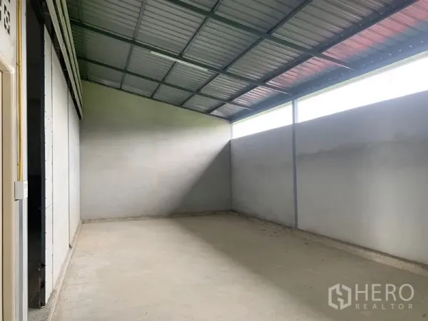 Warehouse for rent or sale in Sai Noi, Nonthaburi - Empty warehouse bay with a sloped metal roof, clerestory windows, and a smooth concrete floor.