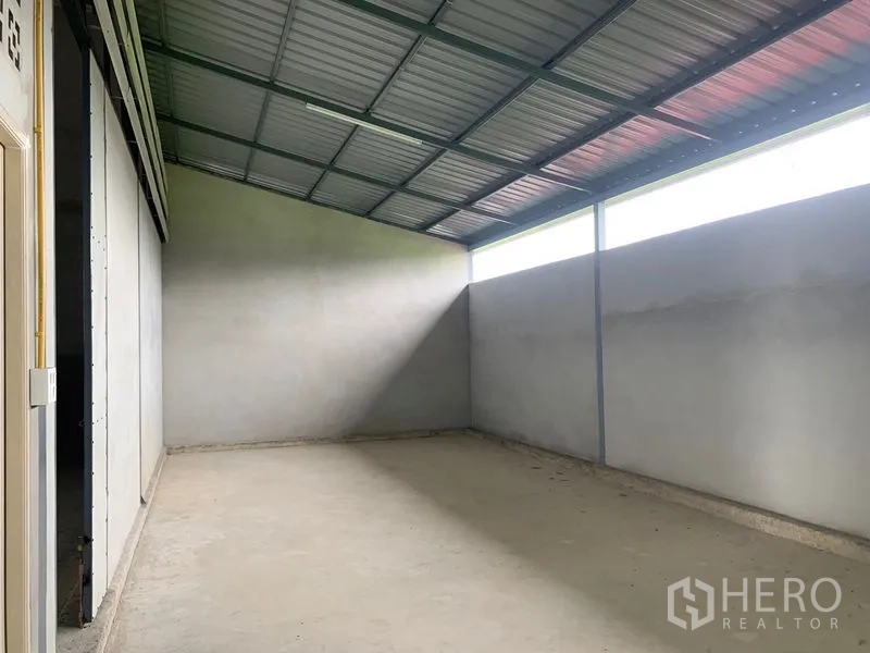 Warehouse for rent or sale in Sai Noi, Nonthaburi - Empty warehouse bay with a sloped metal roof, clerestory windows, and a smooth concrete floor.