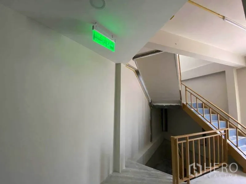 Retail Space for rent in Khlong Toei, Bangkok - Internal stairwell with handrails and an illuminated green exit sign.
