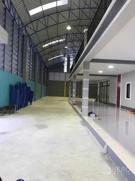 Warehouse for rent in Bang Pakong, Chachoengsao - Spacious warehouse aisle with high arched steel roof, ventilation louvers and adjacent mezzanine office.