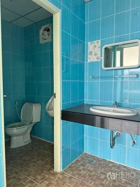 Warehouse for rent in Bang Phli, Samut Prakan - Blue-tiled restroom with toilet, urinal, sink and mirror.