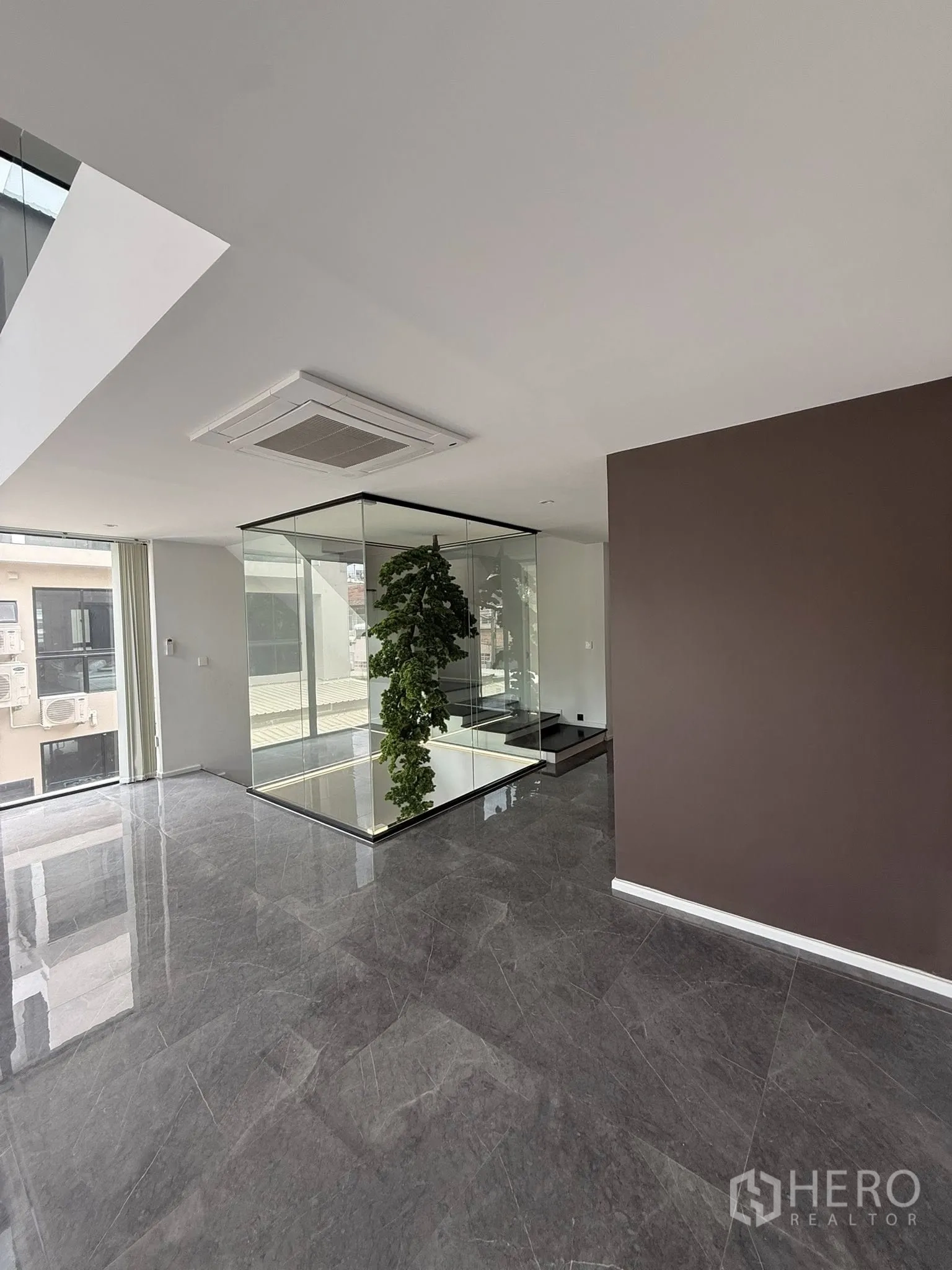 Home Office for rent or sale in Lat Phrao, Bangkok - Polished marble-floored hall showcasing a glass atrium and indoor greenery.