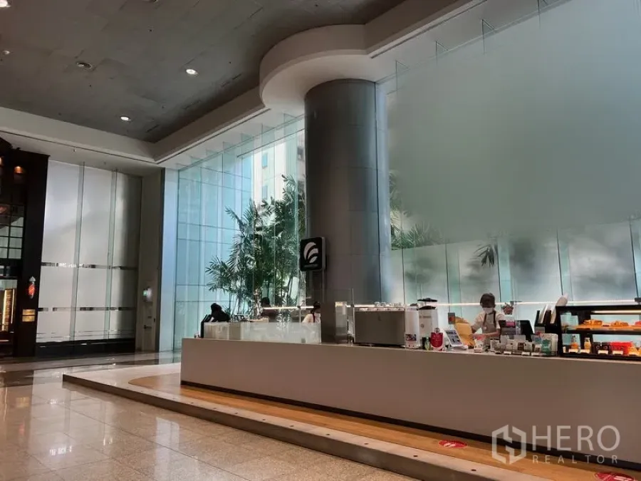 Retail Space for rent in Bang Rak, Bangkok - Modern Silom lobby with high ceilings, floor‑to‑ceiling glass and a built‑in retail counter on polished stone floors.
