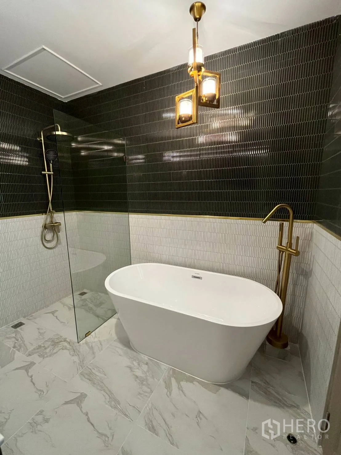 Townhouse for rent in Khlong Toei, Bangkok - Bathroom corner showing tub, gold fixtures, glass screen, and pendant light.