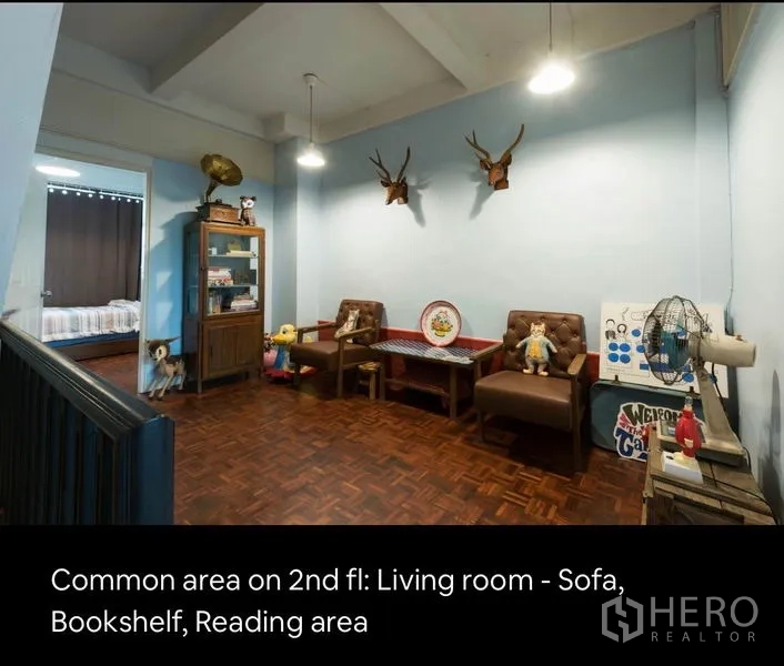 Townhouse for rent in Khlong Toei, Bangkok - Second-floor common area with sofa seating, bookshelf and reading nook on parquet flooring.