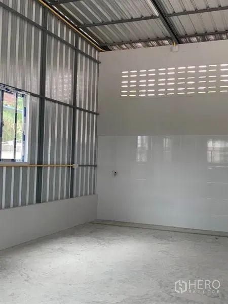 Warehouse for rent or sale in Thanyaburi, Pathum Thani - Bright storage bay with side windows, tiled lower walls and concrete floor.