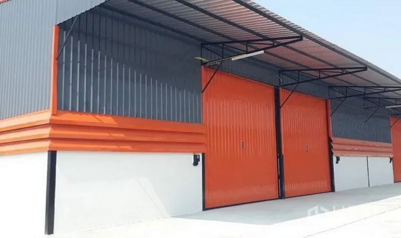 货栈 出租在Lam Luk Ka, Pathum Thani - 一排现代仓库，橙色滑门与钢制雨棚覆盖装卸位。