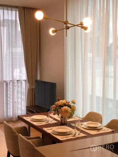 Condominium for rent - Close-up of the dining table under a brass chandelier and sheer drapes.
