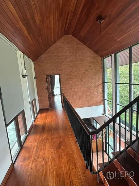 Detached House for rent in Bang Phli, Samut Prakan - Upper hallway with vaulted timber ceiling, brick feature wall, large windows and wood floors.