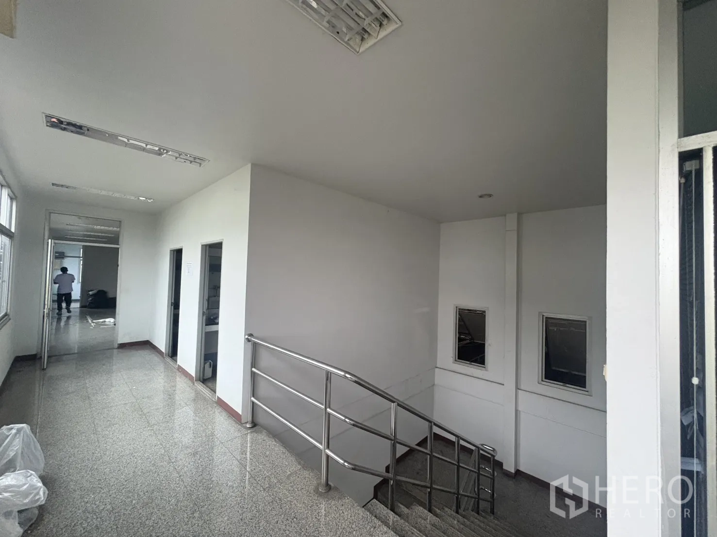 Factory for rent in Khlong Toei, Bangkok - Bright corridor with stainless-steel staircase and office doorways.