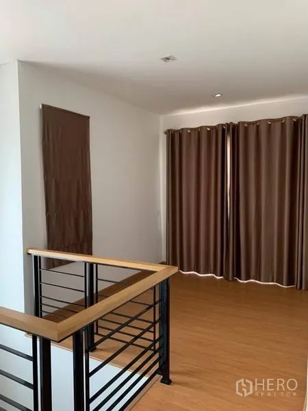 独立式住宅 出售在Suan Luang, Bangkok - 二楼休闲区，木地板与落地厚窗帘。