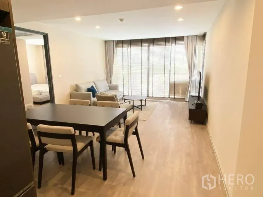 Condominium for rent in Pathum Wan, Bangkok - View from kitchen toward open-plan dining and lounge facing floor-to-ceiling balcony doors.
