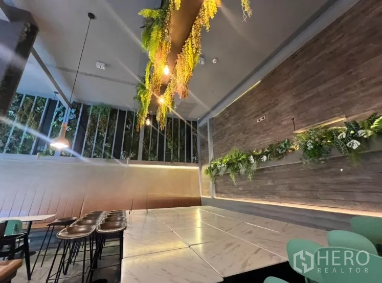 Retail Space for rent - Stylish dining area with marble tables, wood feature wall and hanging greenery under high ceilings.