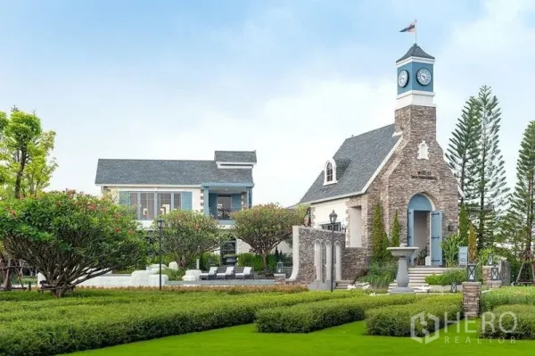 Detached House for rent or sale in Prawet, Bangkok - Community clubhouse with a clock tower, landscaped gardens and poolside seating.
