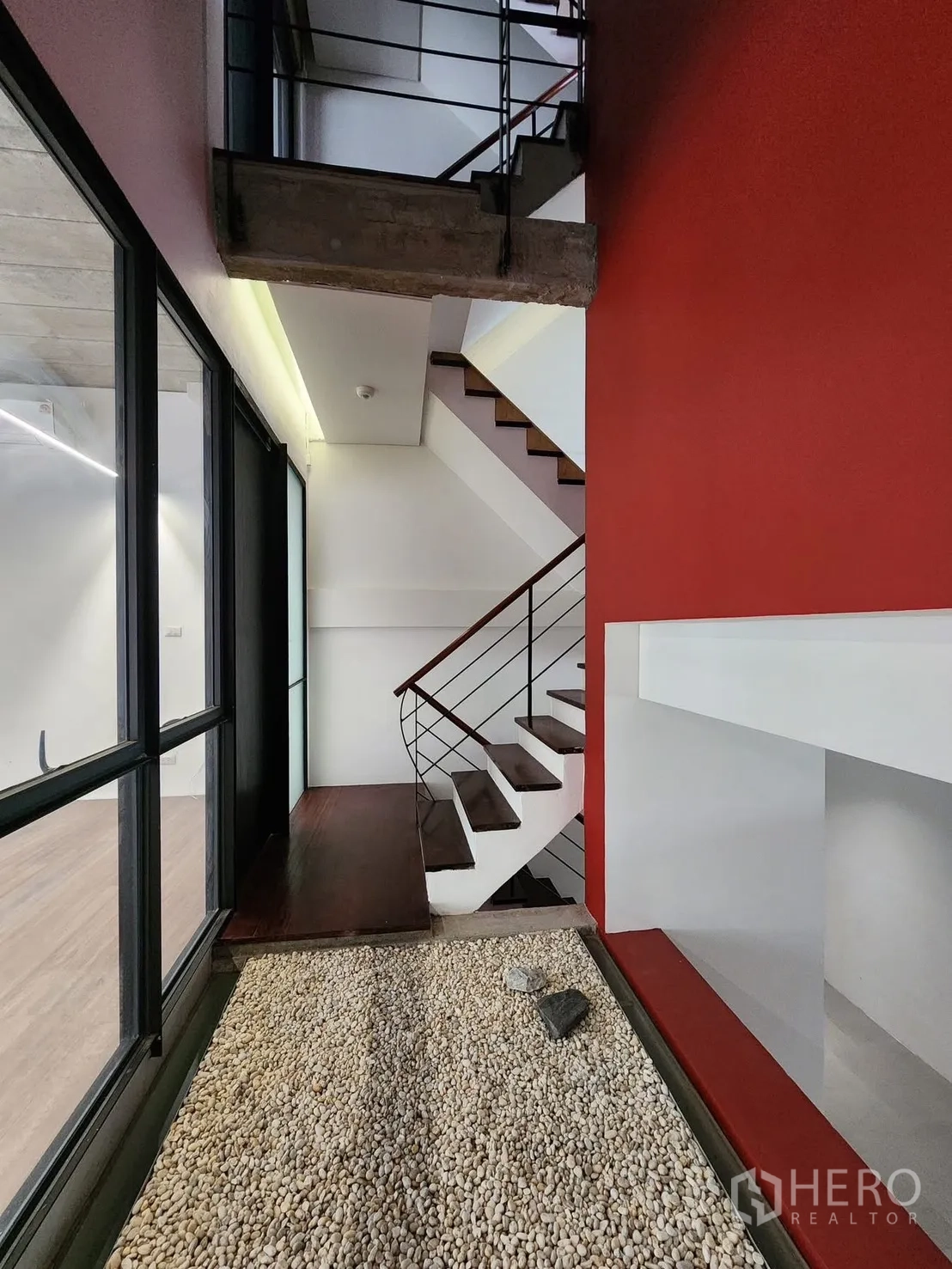 Home Office for rent in Chatuchak, Bangkok - Hallway with indoor pebble garden beside stairs and red accent wall.