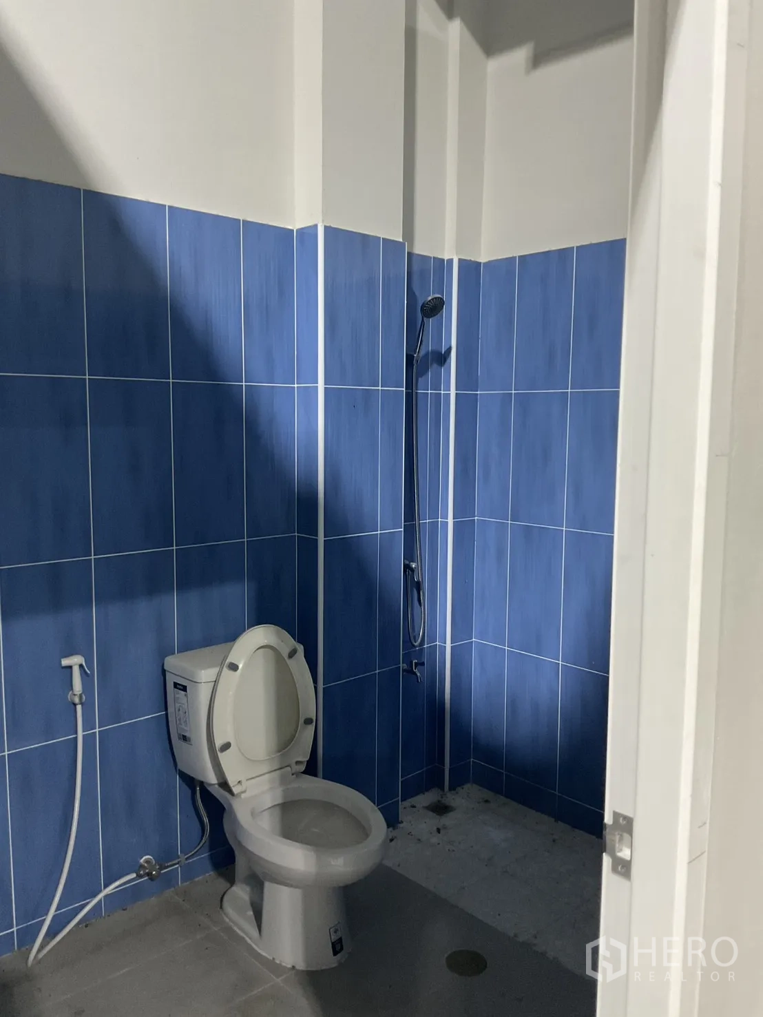 Warehouse for rent in Bang Bua Thong, Nonthaburi - Warehouse restroom with blue wall tiles, shower, and toilet.