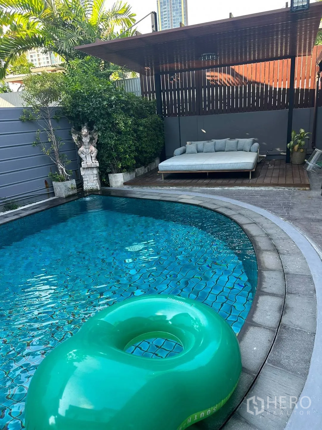 Detached House for rent in Watthana, Bangkok - Private swimming pool with daybed under pergola and lush greenery.