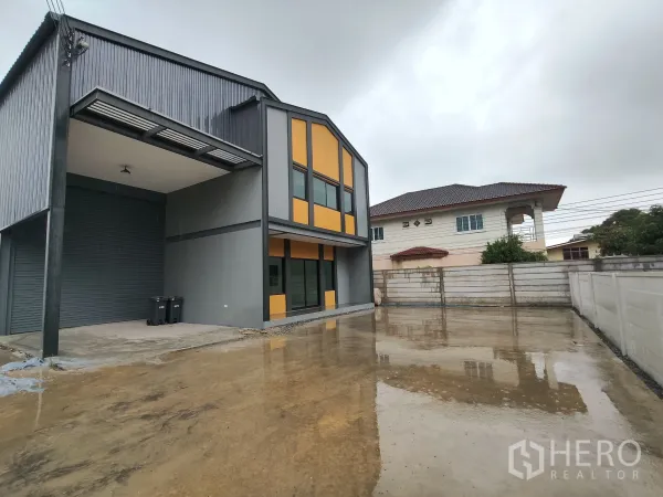 Warehouse for rent or sale in Bang Yai, Nonthaburi - Wide concrete parking and truck maneuvering area beside the contemporary warehouse and office building.