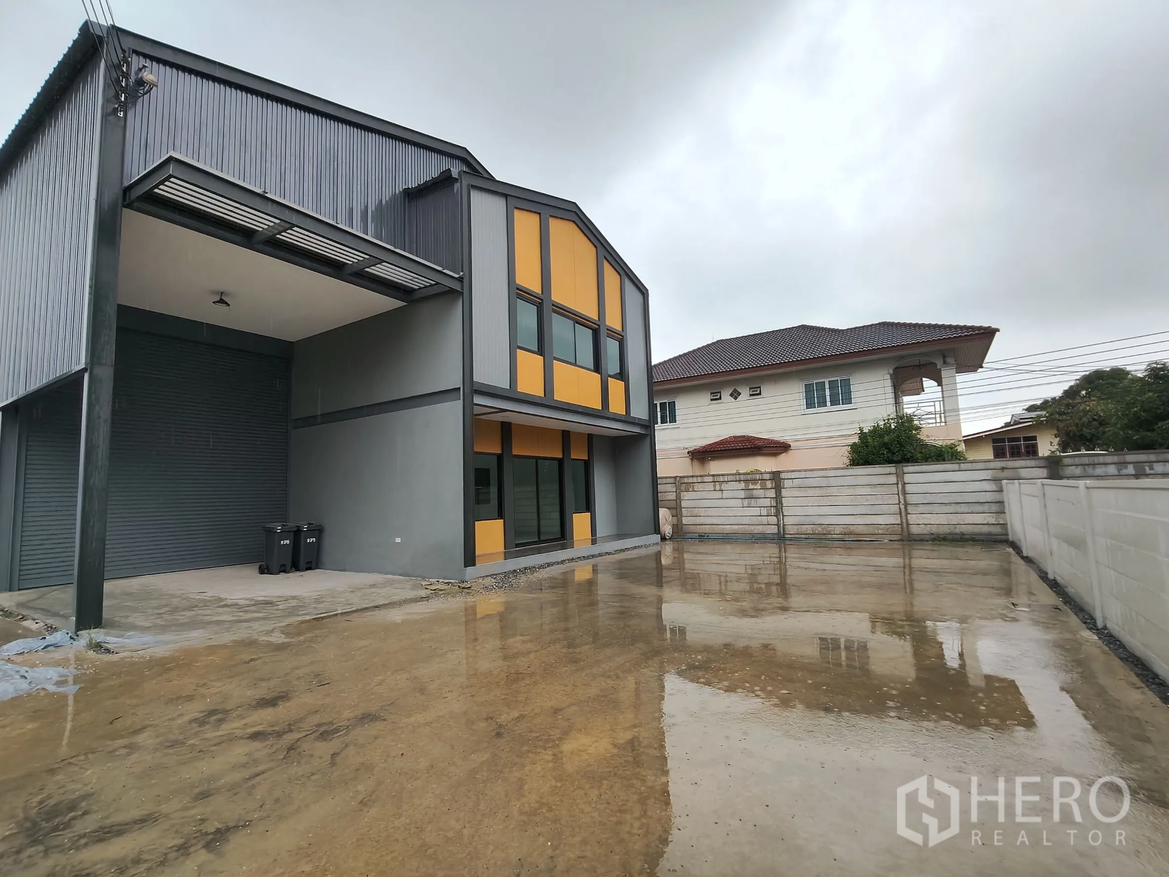 Warehouse for rent or sale in Bang Yai, Nonthaburi - Wide concrete parking and truck maneuvering area beside the contemporary warehouse and office building.