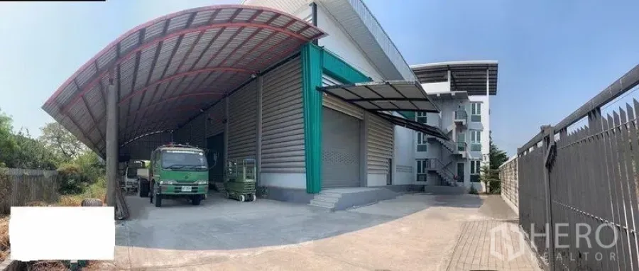 Warehouse for rent in Lak Si, Bangkok - Modern warehouse exterior in Lak Si, Bangkok with covered loading bay, wide driveway and roll-up doors.
