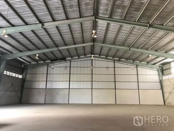 Warehouse for rent in Sai Noi, Nonthaburi - Column-free warehouse hall with metal cladding walls and bright high-bay lights.