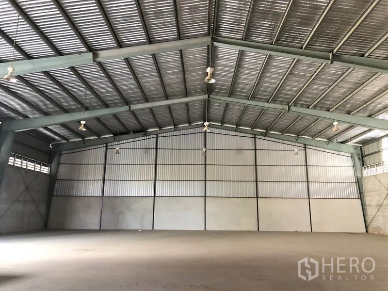 Warehouse for rent in Sai Noi, Nonthaburi - Column-free warehouse hall with metal cladding walls and bright high-bay lights.