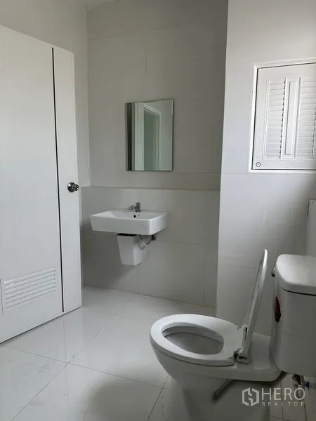 工厂 出租在Khlong Luang, Pathum Thani - 现代卫生间，马桶、壁挂洗手盆与镜子，白色装饰。