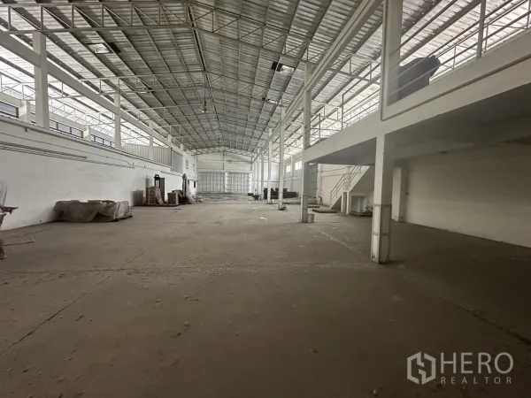 Factory for rent or sale in Prawet, Bangkok - Spacious warehouse interior with high steel-truss roof, skylights and a mezzanine.