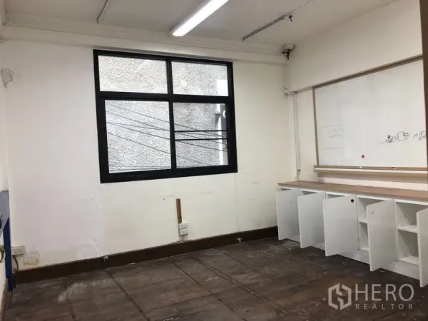 Shophouse for rent - Workroom with black-framed window, built-in storage cabinets and wooden floor.