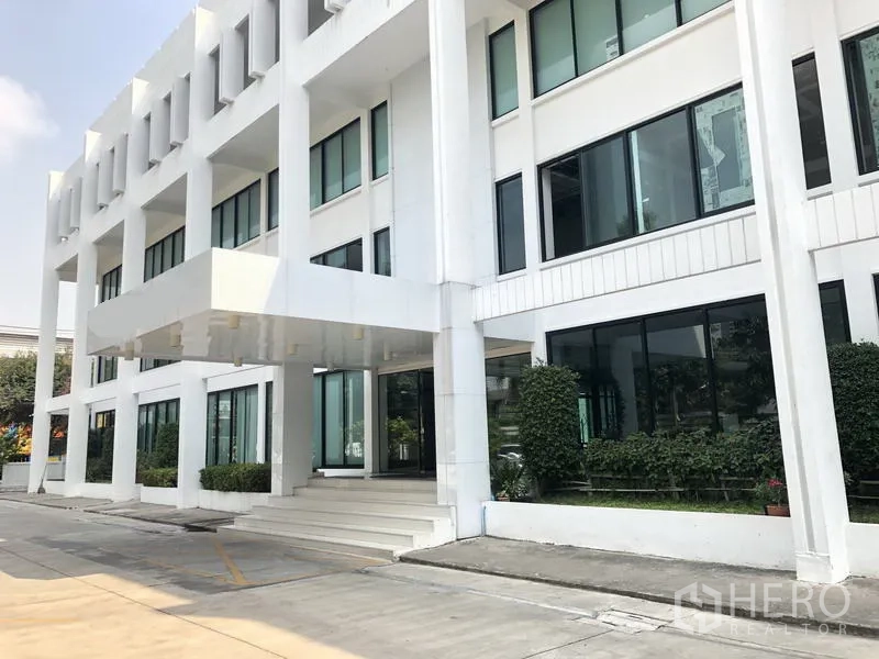 Office Space for rent in Khlong Toei, Bangkok - Modern white low-rise office building with large windows, covered entrance canopy and driveway landscaping in Phra Khanong, Bangkok.