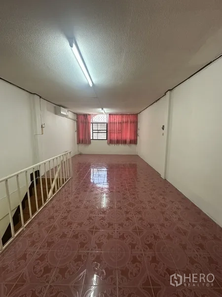 Shophouse for rent or sale in Phra Khanong, Bangkok - Upper floor room with pink ceramic tiles, window with red curtains, and stair railing.